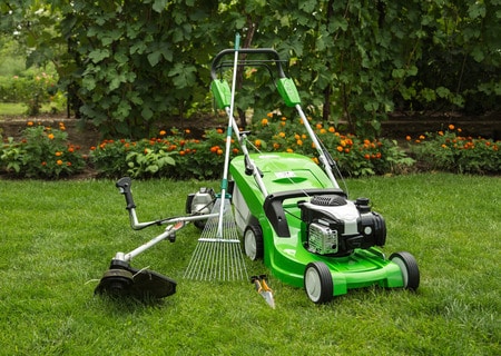 26072069 - green lawnmower, weed trimmer, rake and secateurs in the garden.  Copyright: <a href='https://www.123rf.com/profile_vitalliy'>vitalliy / 123RF Stock Photo</a>